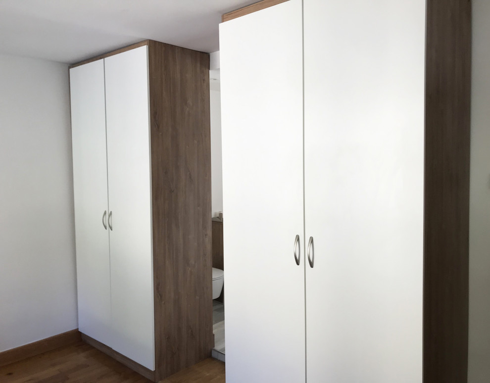 Mid-sized contemporary gender-neutral walk-in wardrobe in Paris with flat-panel cabinets, medium wood cabinets, medium hardwood floors and brown floor.