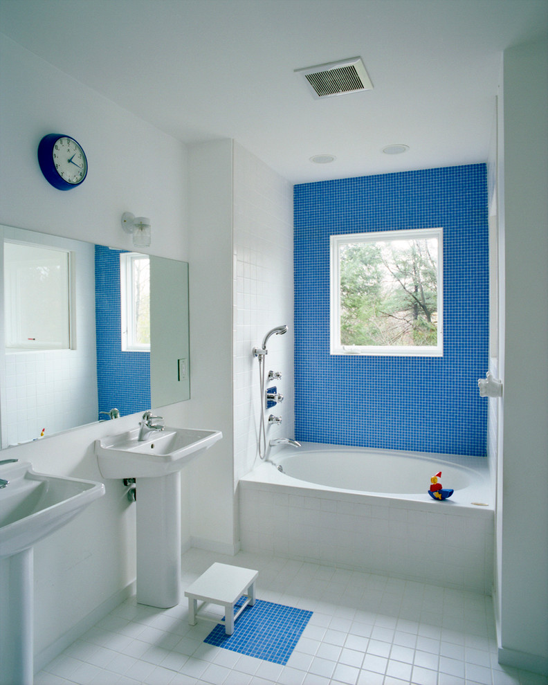 Inspiration for a mid-sized modern kids bathroom in Boston with an alcove tub, a shower/bathtub combo, blue tile, white tile, mosaic tile, white walls, porcelain floors and a pedestal sink.