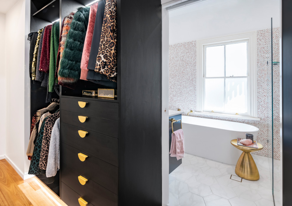 Inspiration for a small contemporary gender-neutral walk-in wardrobe in Brisbane with flat-panel cabinets, dark wood cabinets and light hardwood floors.