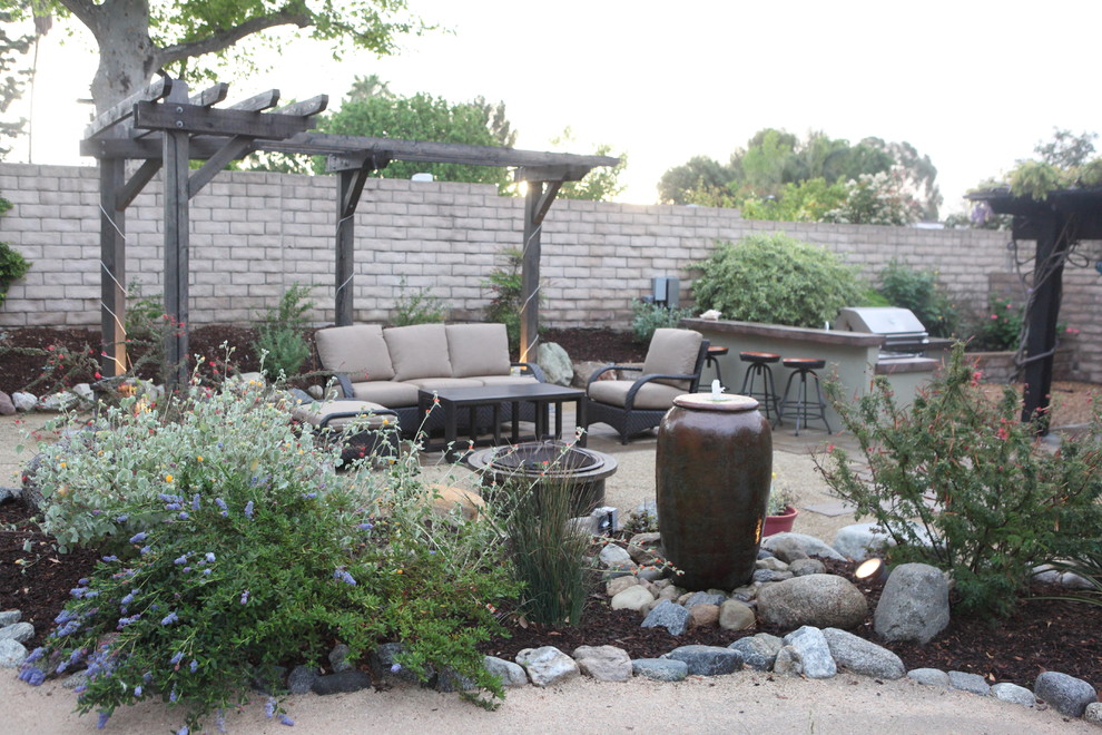 Design ideas for a country backyard patio in Los Angeles with natural stone pavers, a water feature and a pergola.