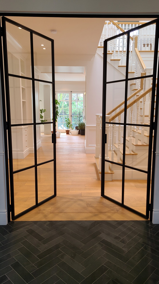 Photo of a large transitional foyer in Montreal with white walls, medium hardwood floors, a single front door, a brown front door, yellow floor and decorative wall panelling.