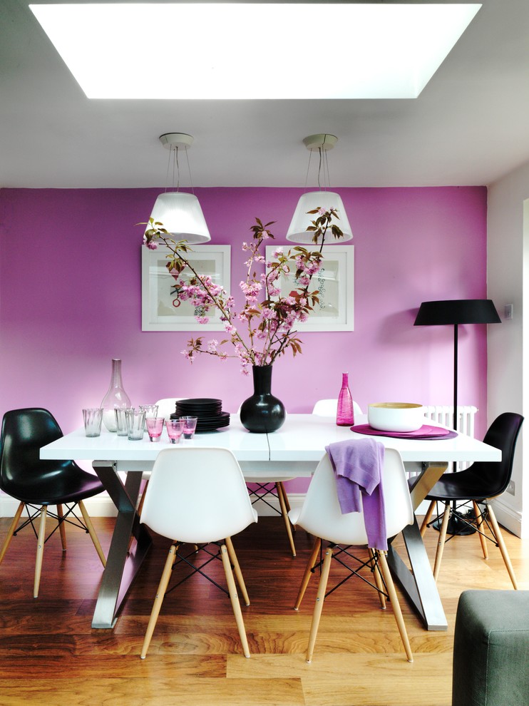 Inspiration for a contemporary dining room in London with pink walls and medium hardwood floors.