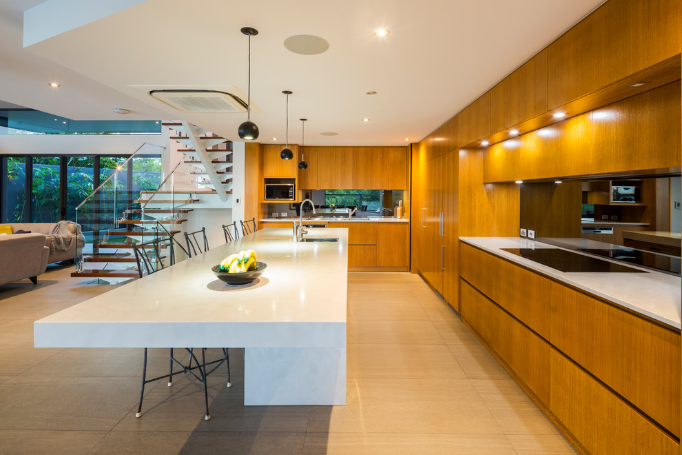 Photo of a contemporary galley open plan kitchen in Other with with island, an undermount sink, flat-panel cabinets, medium wood cabinets, mirror splashback, beige floor and white benchtop.