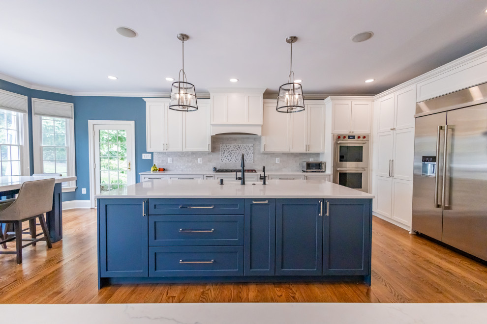 Inspiration for a large transitional u-shaped medium tone wood floor and brown floor eat-in kitchen remodel in Baltimore with a farmhouse sink, shaker cabinets, blue cabinets, quartz countertops, white backsplash, marble backsplash, stainless steel appliances, an island and white countertops