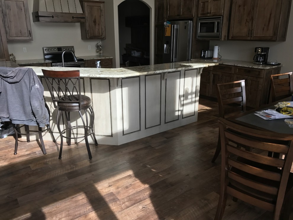 Inspiration for a large timeless u-shaped dark wood floor and brown floor open concept kitchen remodel with flat-panel cabinets, distressed cabinets, granite countertops, a double-bowl sink, stainless steel appliances and an island