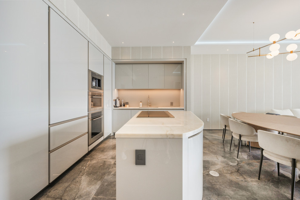 Eat-in kitchen - mid-sized transitional l-shaped porcelain tile and gray floor eat-in kitchen idea in Miami with an undermount sink, flat-panel cabinets, beige cabinets, quartzite countertops, beige backsplash, glass sheet backsplash, paneled appliances, an island and beige countertops
