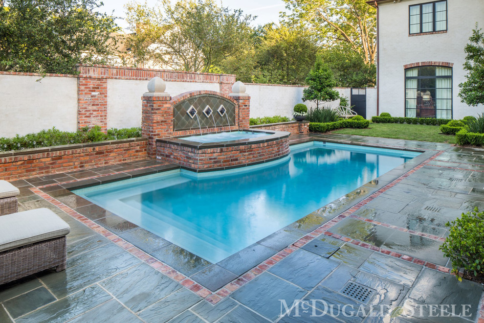 Photo of a mid-sized traditional side yard rectangular pool in Houston with a water feature and natural stone pavers.
