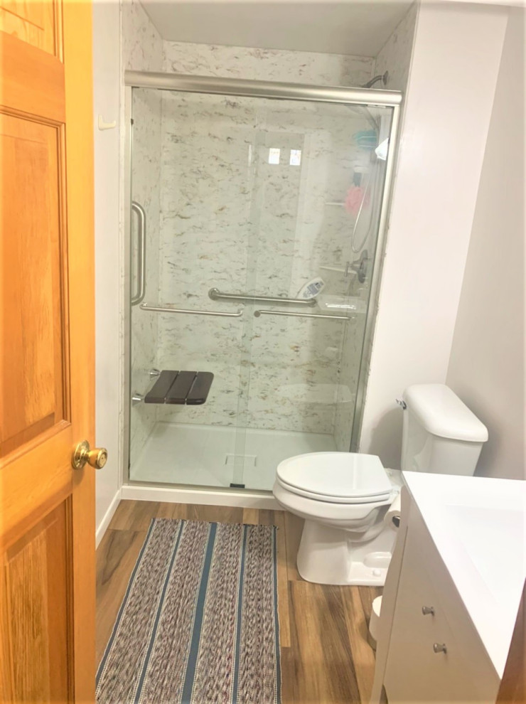 Foto på ett mellanstort amerikanskt vit badrum med dusch, med släta luckor, vita skåp, vita väggar, marmorbänkskiva och brunt golv