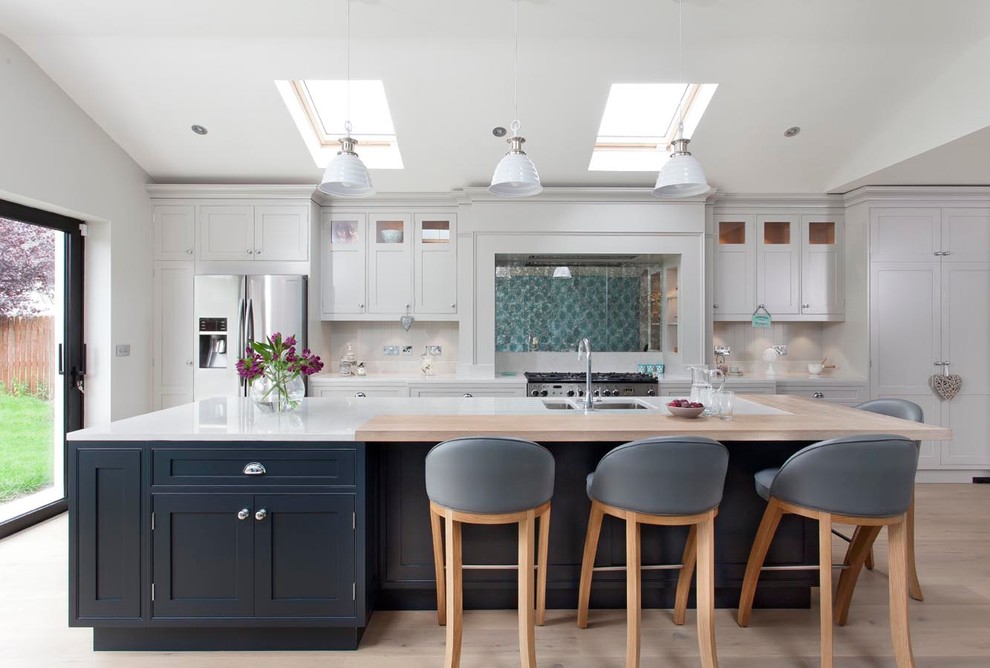 Inspiration for a transitional light wood floor kitchen remodel in Dublin with a double-bowl sink, shaker cabinets, white cabinets, stainless steel appliances and an island