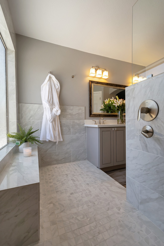 Photo of a mid-sized transitional master bathroom in Phoenix with raised-panel cabinets, grey cabinets, an open shower, gray tile, porcelain tile, grey walls, porcelain floors, a drop-in sink, engineered quartz benchtops, grey floor, an open shower and white benchtops.