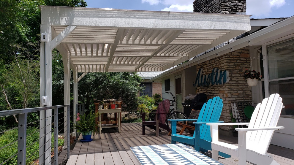 This is an example of a large traditional backyard deck in Austin with a pergola.