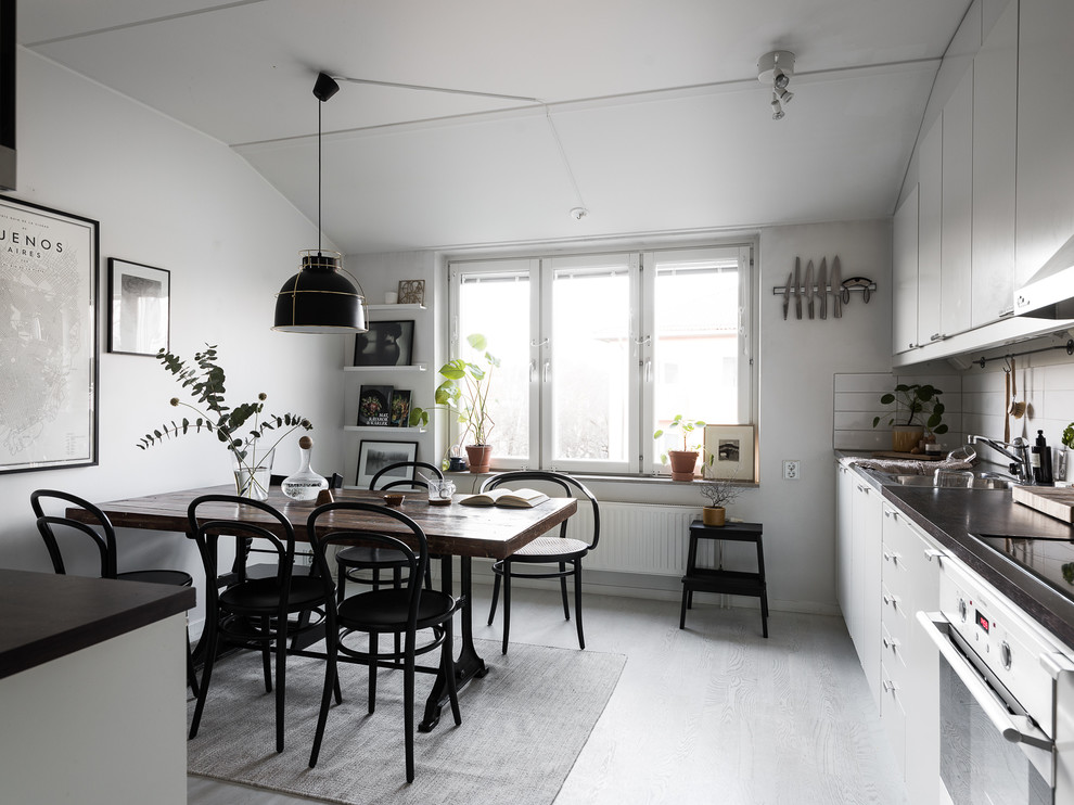 Inspiration for a scandinavian single-wall eat-in kitchen in Stockholm with flat-panel cabinets, white cabinets, laminate floors, no island, grey floor, white splashback and white appliances.