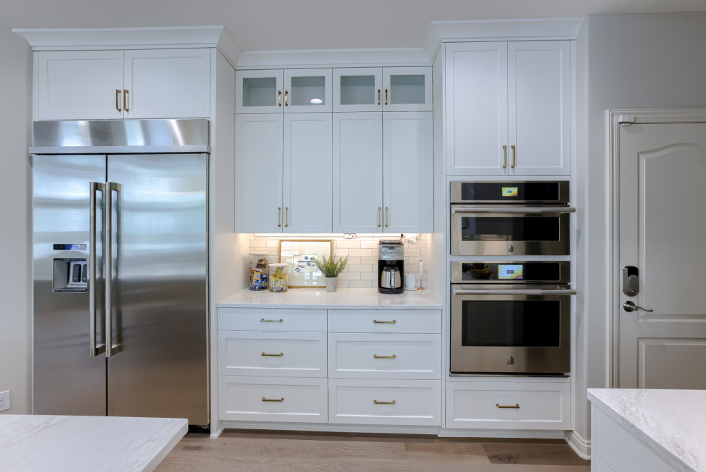 Transitional light wood floor and beige floor open concept kitchen photo with an undermount sink, white cabinets, quartzite countertops, multicolored backsplash, stainless steel appliances and an island