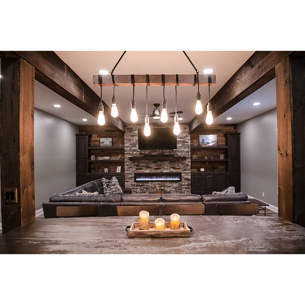 Photo of a large rustic walk-out basement in Other with a home cinema, grey walls, vinyl flooring, a standard fireplace, a brick fireplace surround, brown floors, exposed beams and wood walls.