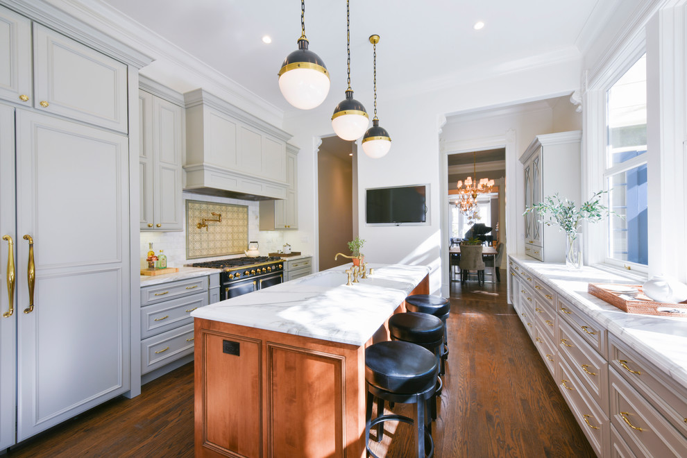 Design ideas for a mid-sized traditional galley kitchen in San Francisco with an undermount sink, grey cabinets, quartzite benchtops, white splashback, subway tile splashback, black appliances, medium hardwood floors, with island, brown floor, white benchtop and recessed-panel cabinets.