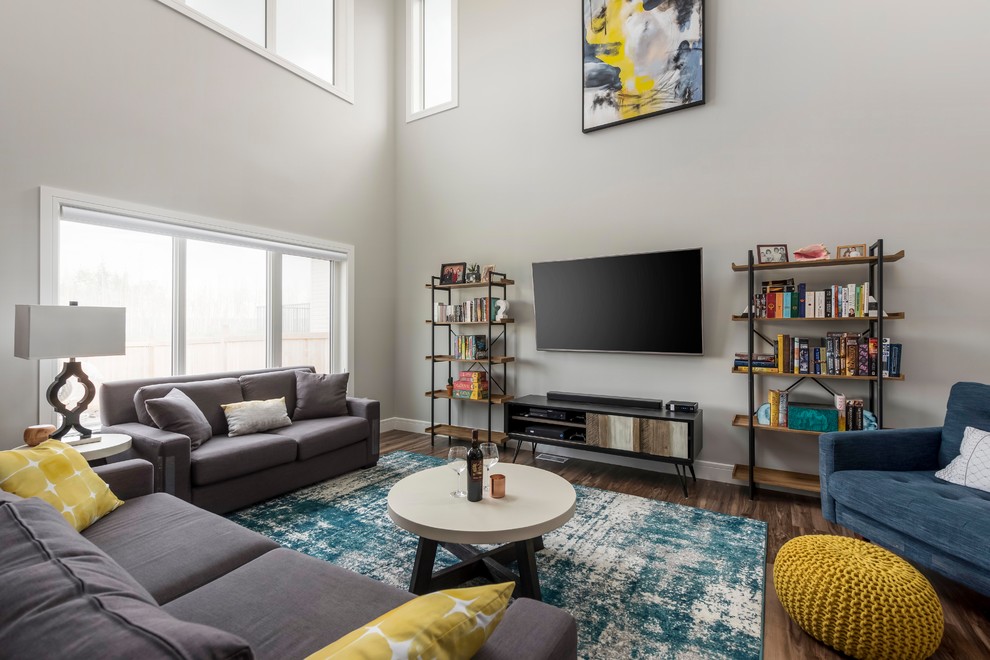 This is an example of a transitional living room in Edmonton with grey walls, dark hardwood floors, a wall-mounted tv and brown floor.