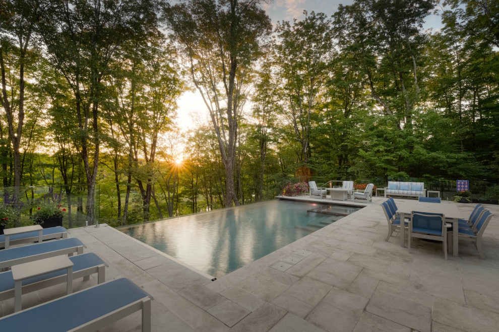 Design ideas for a medium sized classic back rectangular infinity swimming pool in Toronto with with pool landscaping and natural stone paving.