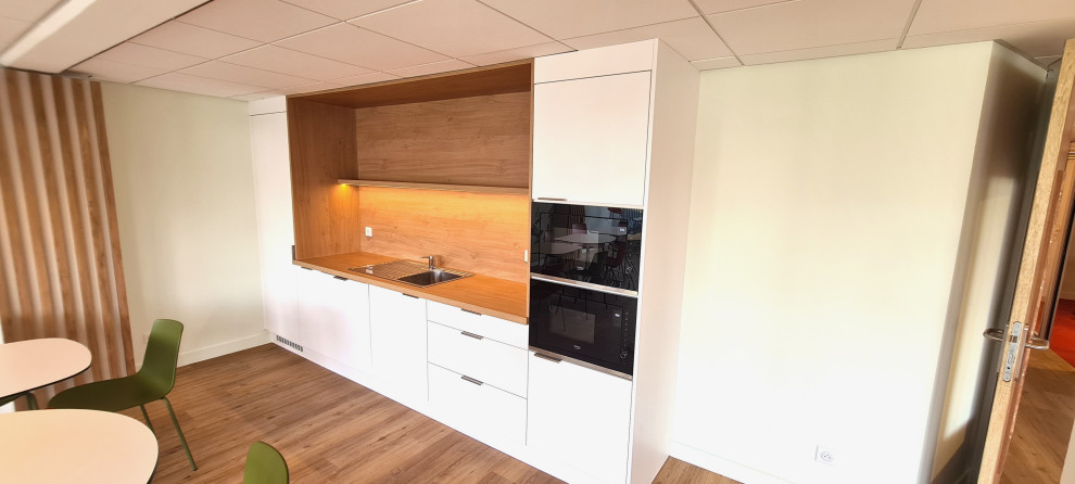 Inspiration for a small modern single-wall open plan kitchen in Lille with an undermount sink, beaded inset cabinets, white cabinets, wood benchtops, brown splashback, timber splashback, stainless steel appliances, medium hardwood floors, no island, brown floor and brown benchtop.