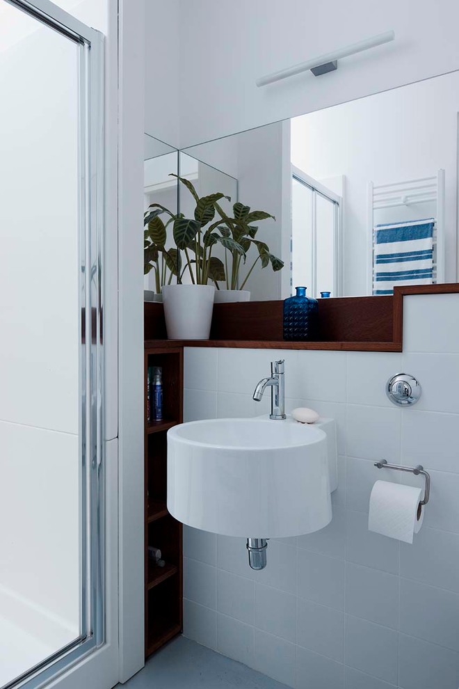 Photo of a small contemporary master bathroom in Dublin with a curbless shower, a wall-mount toilet, white tile, ceramic tile, white walls, vinyl floors, a wall-mount sink, blue floor and a hinged shower door.
