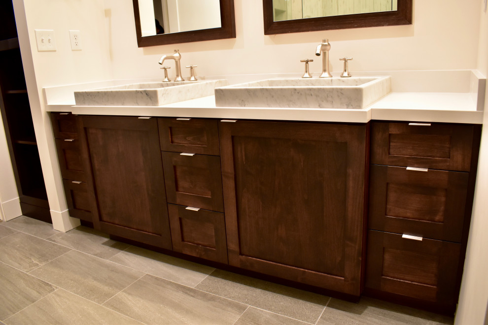 Example of a mid-sized transitional master corner shower design with shaker cabinets, brown cabinets, a trough sink, quartz countertops and white countertops