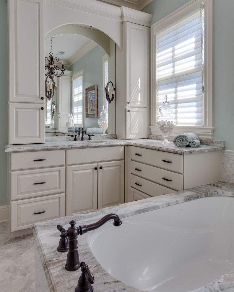 Traditional master bathroom in Nashville with raised-panel cabinets, turquoise cabinets, an undermount tub, blue walls, an undermount sink, granite benchtops, beige floor and multi-coloured benchtops.