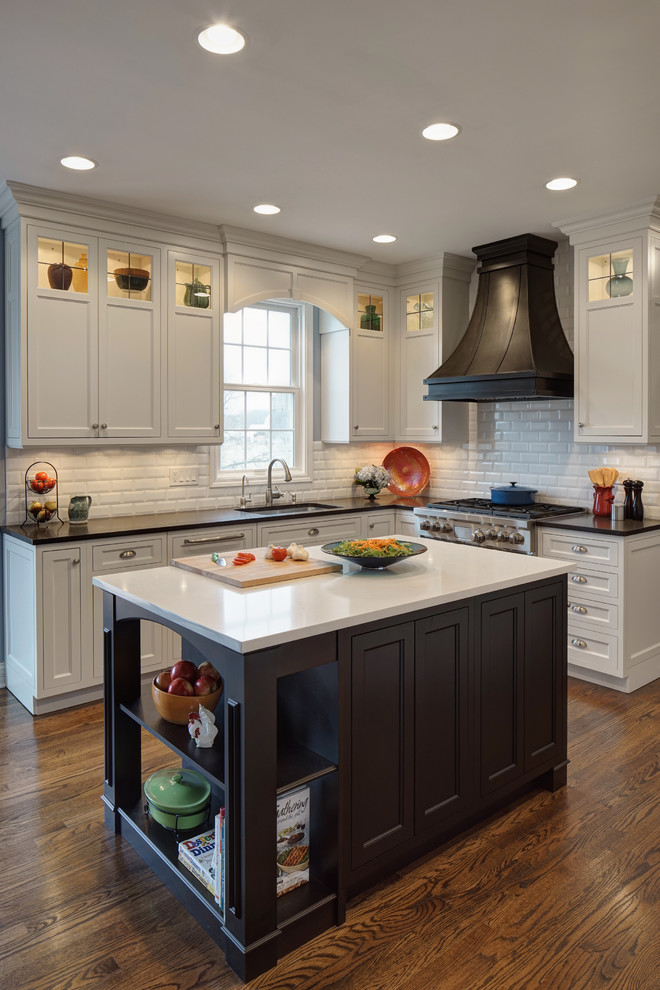 Photo of a mid-sized traditional l-shaped kitchen in Chicago with an undermount sink, beaded inset cabinets, white cabinets, granite benchtops, white splashback, subway tile splashback, stainless steel appliances, dark hardwood floors, with island and multi-coloured benchtop.