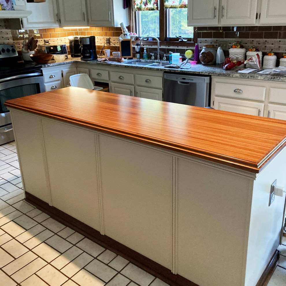 This is an example of a country u-shaped separate kitchen in Other with a double-bowl sink, raised-panel cabinets, white cabinets, wood benchtops, brown splashback, brick splashback, stainless steel appliances, with island, white floor and red benchtop.