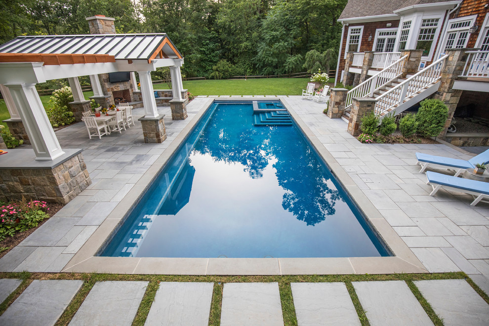 Photo of a traditional backyard rectangular pool in New York with a pool house and concrete pavers.