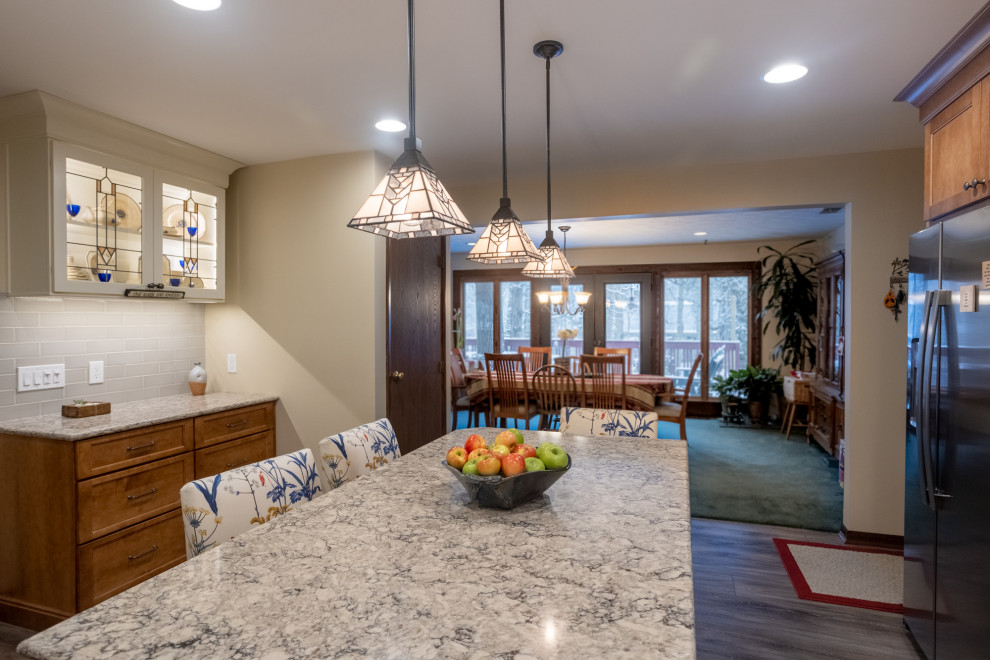 Example of a mid-sized classic u-shaped dark wood floor and brown floor enclosed kitchen design in Cincinnati with a drop-in sink, shaker cabinets, white cabinets, granite countertops, subway tile backsplash, stainless steel appliances, an island, multicolored countertops and gray backsplash