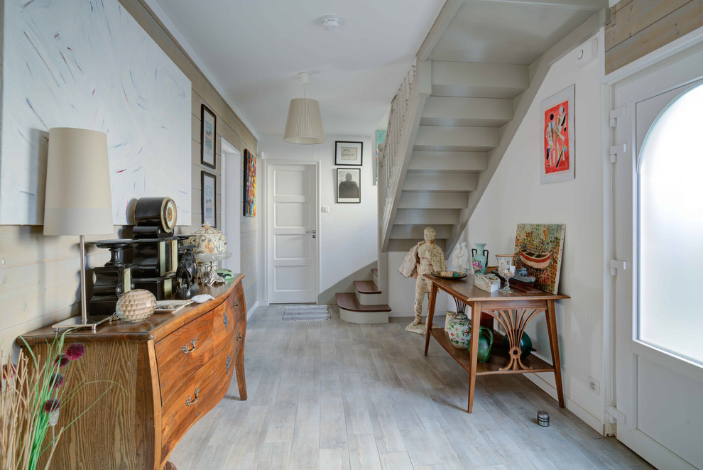 Aménagement d'une entrée bord de mer avec un couloir, un mur blanc, parquet clair, une porte simple, une porte blanche et un sol gris.