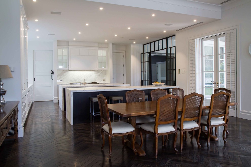 Photo of a large traditional l-shaped open plan kitchen in Melbourne with shaker cabinets, marble benchtops, stone slab splashback, dark hardwood floors and multiple islands.