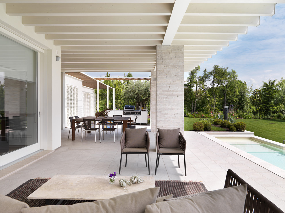 Inspiration for a large contemporary backyard patio in Milan with an outdoor kitchen and a pergola.