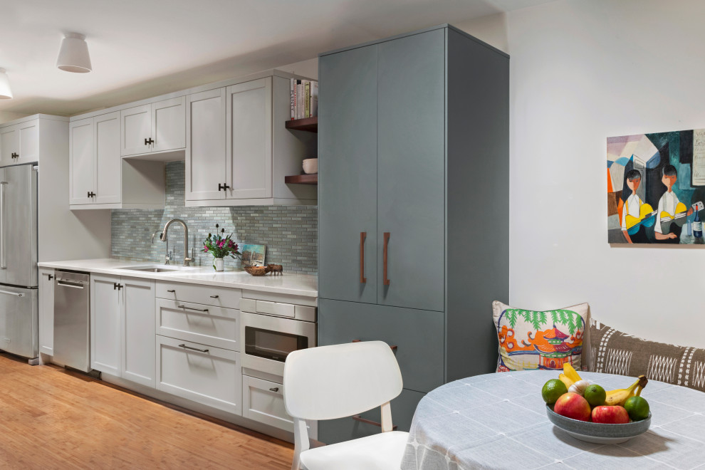 Inspiration for a small transitional galley separate kitchen in Seattle with an undermount sink, shaker cabinets, grey cabinets, quartz benchtops, blue splashback, ceramic splashback, stainless steel appliances, bamboo floors, no island, orange floor and white benchtop.