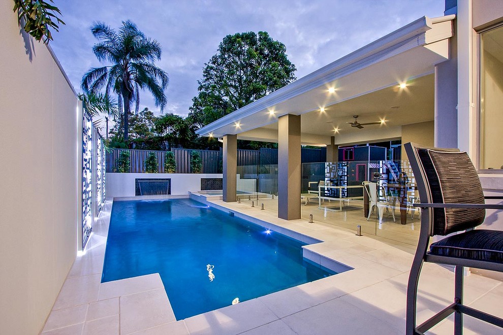 Design ideas for a small modern custom-shaped lap pool in Brisbane with a water feature and natural stone pavers.
