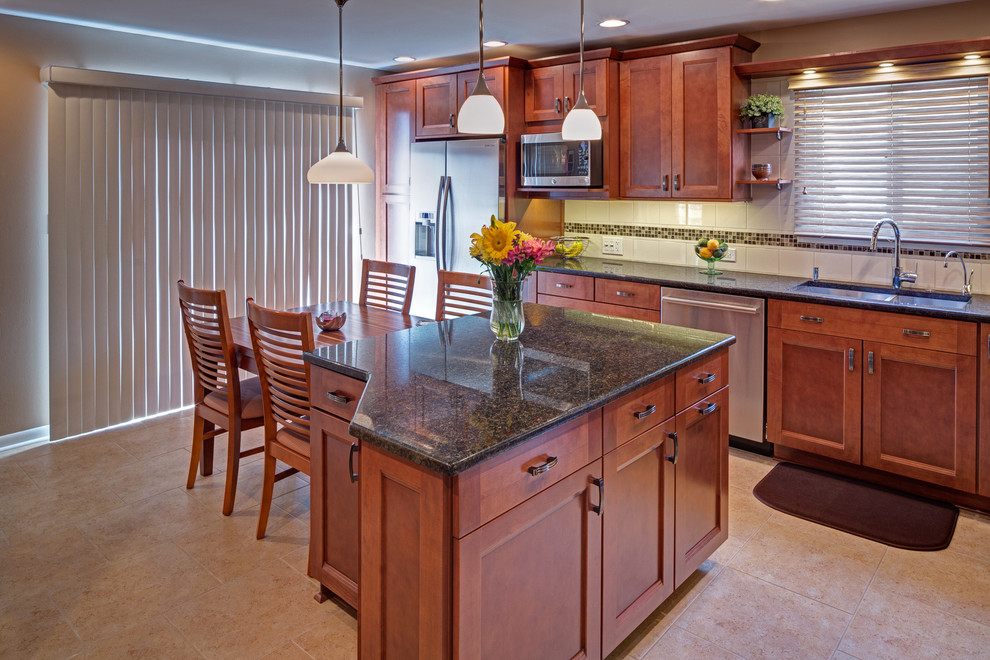 This is an example of a mid-sized transitional l-shaped kitchen in Chicago with an undermount sink, recessed-panel cabinets, medium wood cabinets, quartz benchtops, white splashback, mosaic tile splashback, stainless steel appliances and porcelain floors.