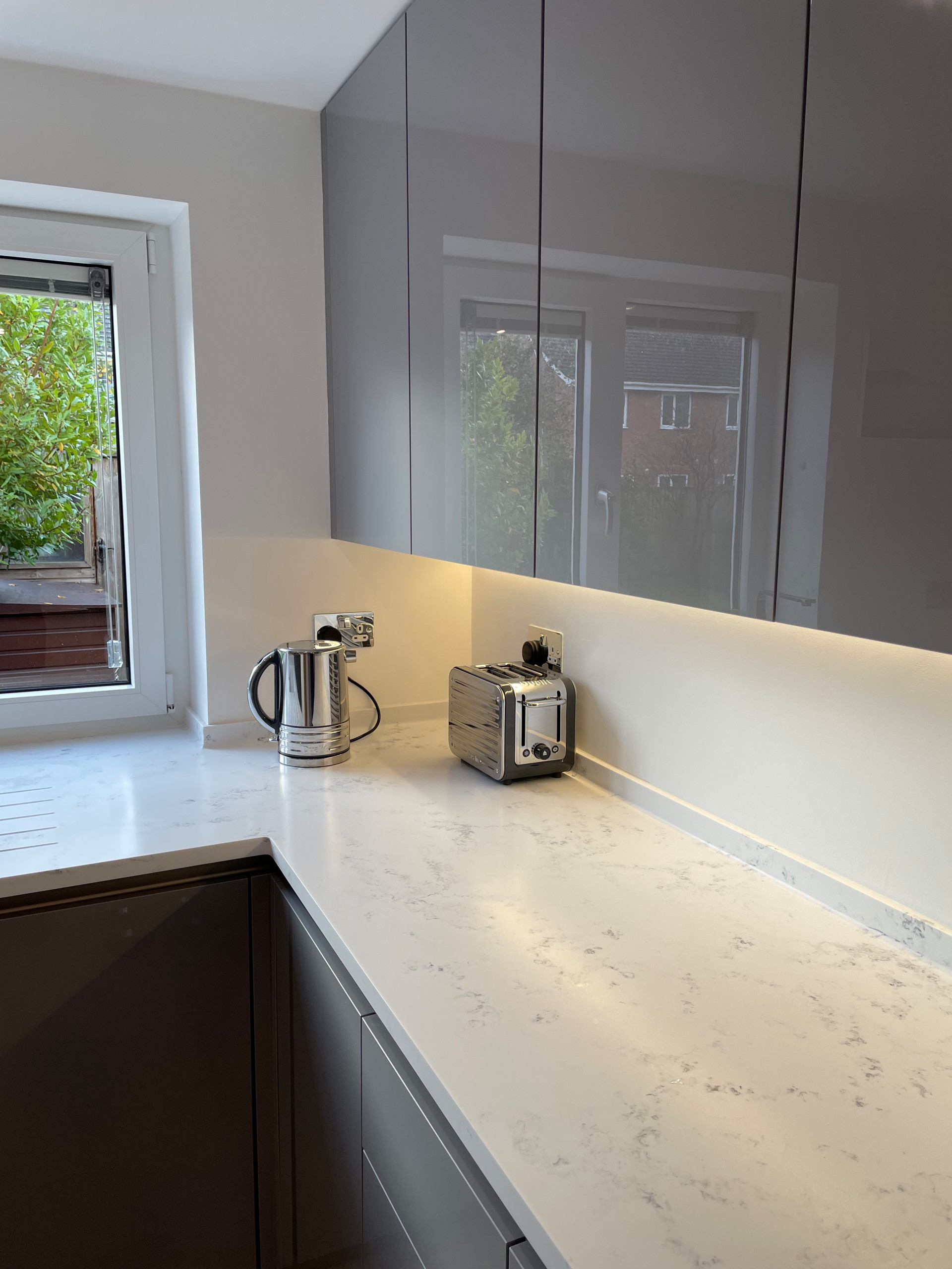 High Gloss Gravel Handleless Kitchen with White and Grey Solid Surface Tops