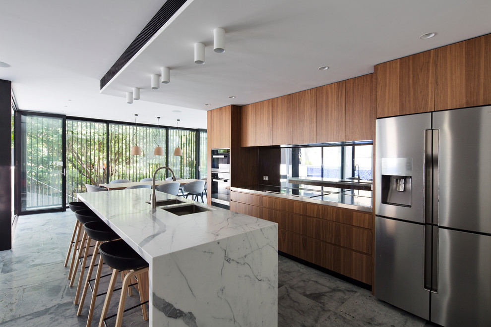 Large contemporary galley kitchen pantry in Sydney with an undermount sink, marble benchtops, mirror splashback, stainless steel appliances and with island.