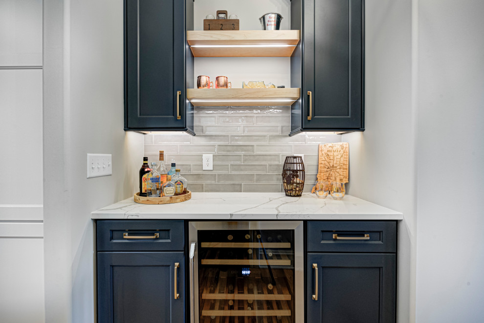 This is an example of a mid-sized transitional single-wall home bar in Indianapolis with shaker cabinets, black cabinets, granite benchtops, subway tile splashback, white benchtop and grey splashback.