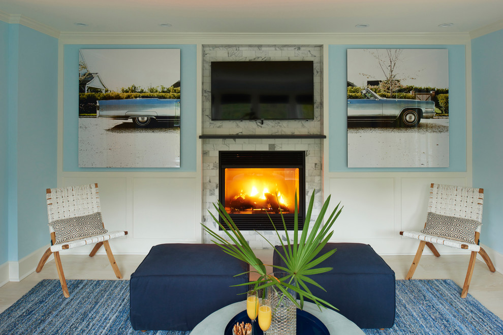 Design ideas for a mid-sized beach style enclosed family room in New York with blue walls, light hardwood floors, a two-sided fireplace, a tile fireplace surround and a wall-mounted tv.