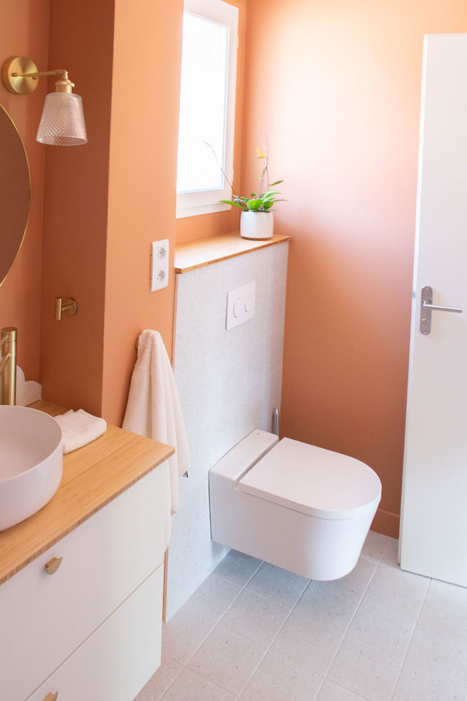 Esempio di una piccola stanza da bagno per bambini minimalista con vasca sottopiano, WC sospeso, piastrelle bianche, piastrelle in ceramica, pareti arancioni, pavimento alla veneziana, top in legno, pavimento grigio e un lavabo