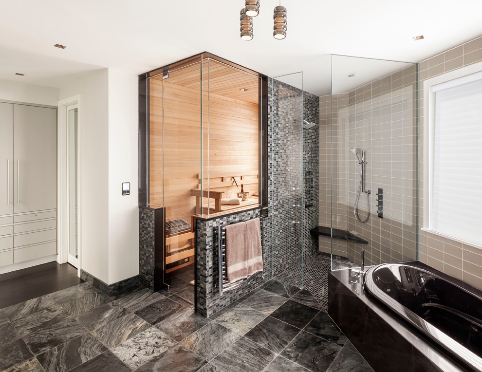 Large contemporary master bathroom in Portland Maine with flat-panel cabinets, grey cabinets, a freestanding tub, a corner shower, black tile, stone tile, white walls and marble floors.