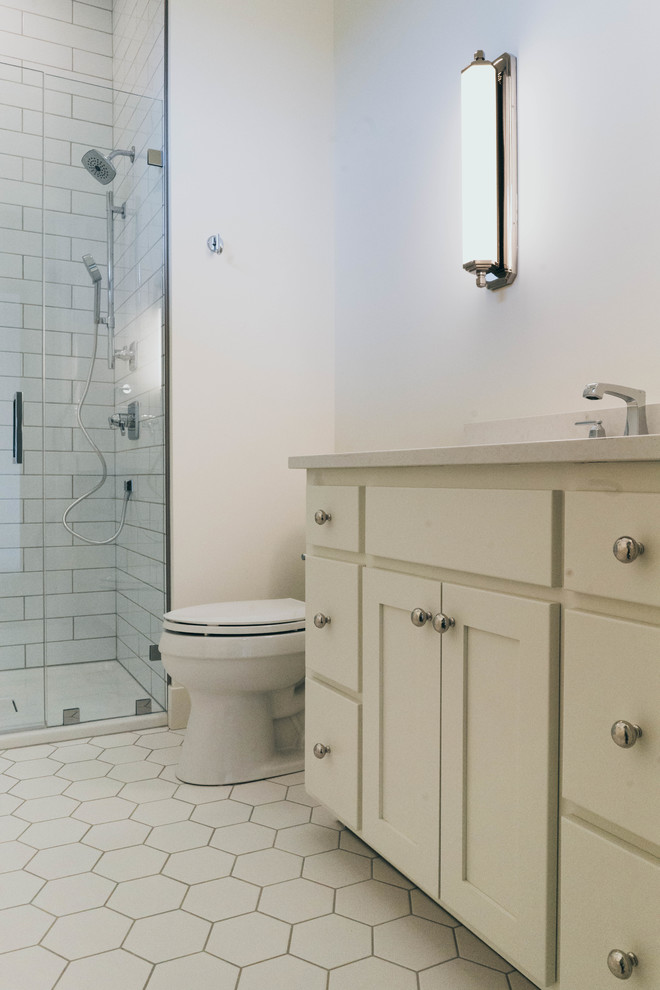 Inspiration for a transitional 3/4 white tile alcove shower remodel in Omaha with shaker cabinets, white cabinets, a two-piece toilet, an undermount sink, quartz countertops, a hinged shower door and white countertops