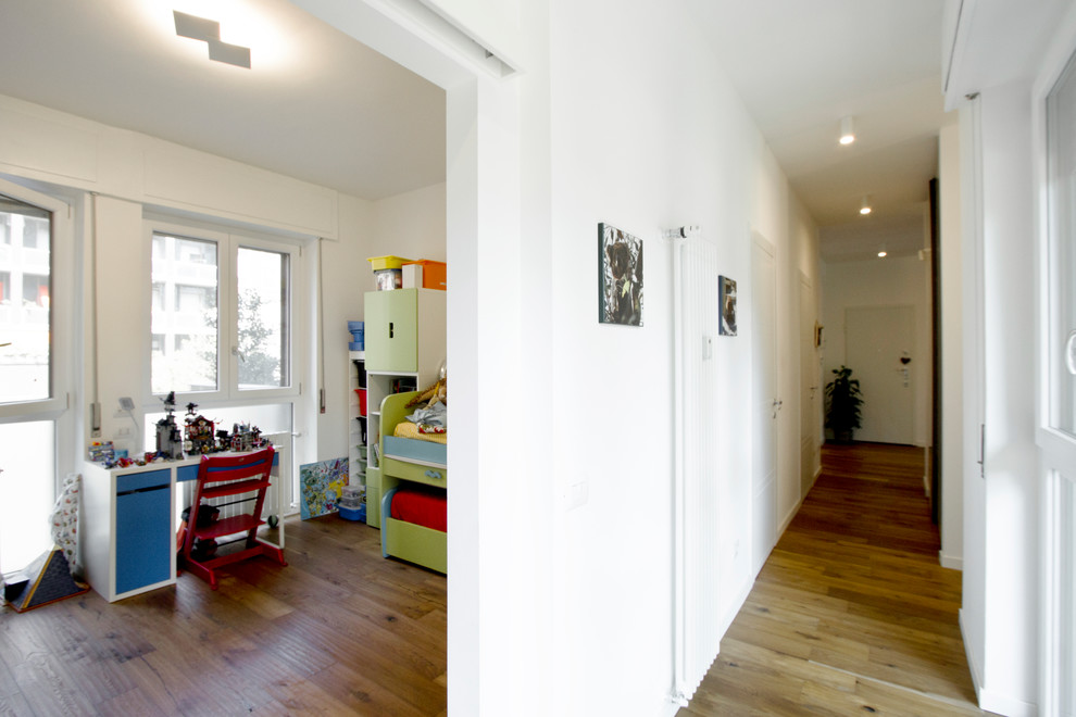 Design ideas for a large contemporary gender-neutral kids' playroom for kids 4-10 years old in Milan with white walls and light hardwood floors.