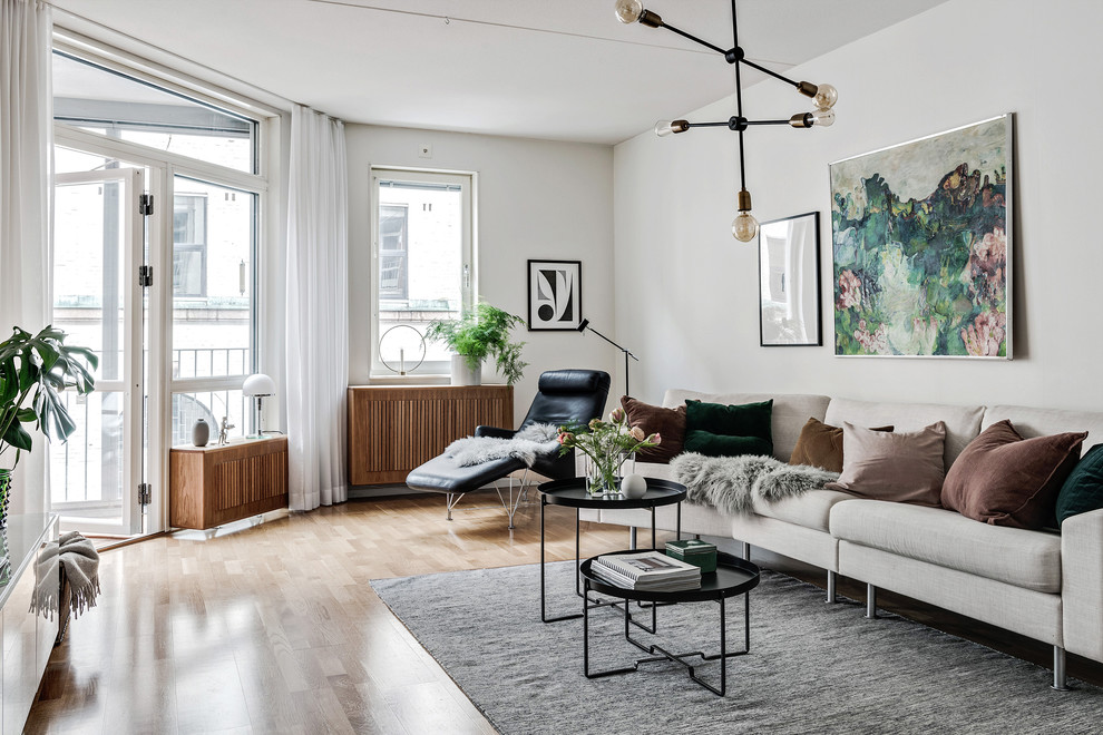 Scandinavian formal enclosed living room in Gothenburg with white walls, beige floor and light hardwood floors.