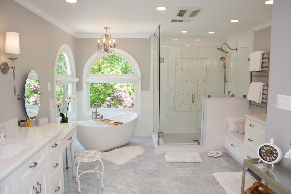Стильный дизайн: большая главная ванная комната в стиле шебби-шик с фасадами с утопленной филенкой, белыми фасадами, отдельно стоящей ванной, душем в нише, раздельным унитазом, белой плиткой, серыми стенами, врезной раковиной, столешницей из искусственного кварца, серым полом, душем с распашными дверями, белой столешницей, сиденьем для душа, тумбой под две раковины и напольной тумбой - последний тренд