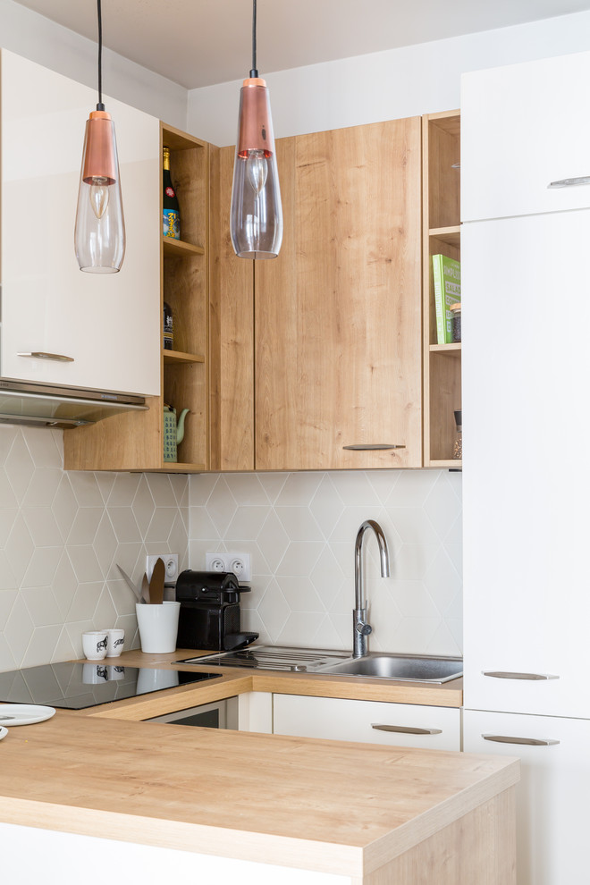 Small scandinavian u-shaped kitchen in Paris with a drop-in sink, flat-panel cabinets, white cabinets, wood benchtops, grey splashback and a peninsula.