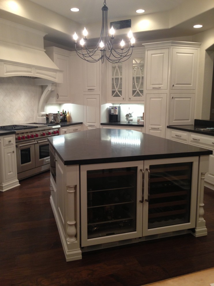 Example of a transitional dark wood floor kitchen design in Phoenix with white cabinets, granite countertops, white backsplash, stainless steel appliances and an island