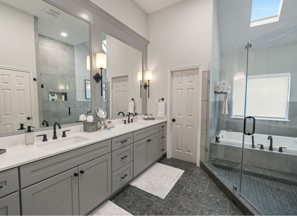 Photo of a large contemporary ensuite wet room bathroom in Houston with shaker cabinets, grey cabinets, a built-in bath, a two-piece toilet, grey walls, ceramic flooring, a submerged sink, engineered stone worktops, black floors, a hinged door, white worktops, a wall niche, double sinks, a built in vanity unit and wainscoting.