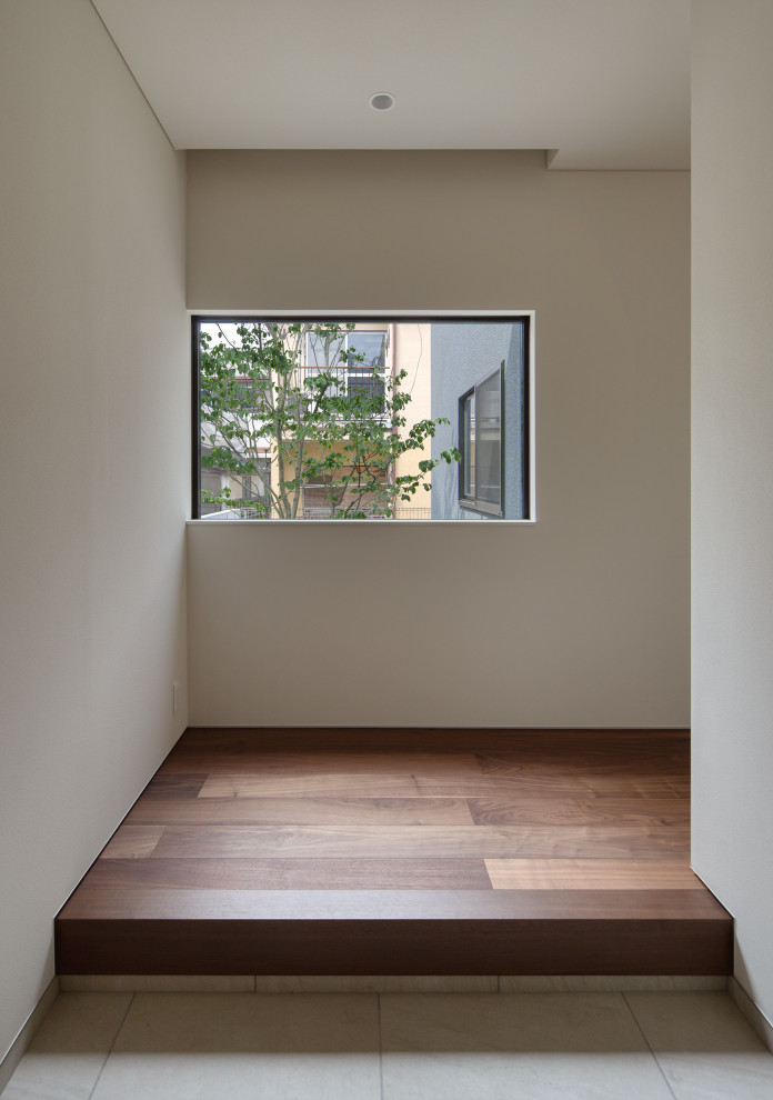 Small modern entry hall in Fukuoka with white walls, dark hardwood floors, a sliding front door, a medium wood front door, brown floor, wallpaper and wood walls.