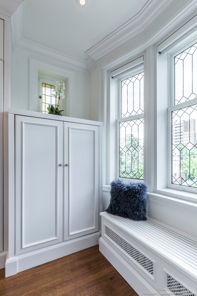 Inspiration for a large traditional walk-in wardrobe for women in Montreal with shaker cabinets, white cabinets, medium hardwood flooring and brown floors.